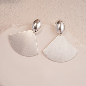 Detailed macro view of silver-toned fan-shaped earrings with brushed texture