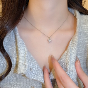 Detail of silver clover pendant with pearls and zircon on model neck with beige sweater