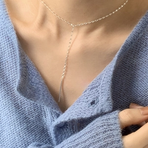 Detailed close-up of a silver Y-shaped minimalist necklace with a polished bar pendant