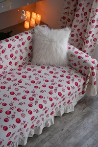 Detailed view of Christmas sofa cover with red festive patterns and elegant ruffles