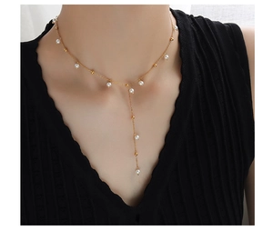 Detail of elegant Y-shaped gold-plated necklace with white pearls on a model neck