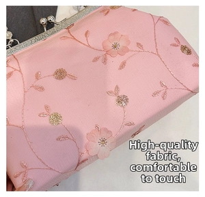 Close-up of pink satin clutch bag featuring delicate floral embroidery and sequins
