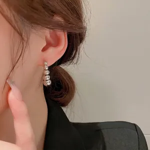Elegant minimalist silver ball drop earrings featuring four graduated beads on model