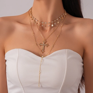 Detailed view of triple-layered gold cross and star pendant necklace on model