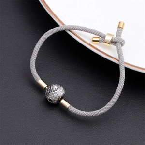 Macro view of grey braided bracelet with gold metal and black white yin yang bead