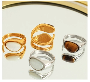 Assorted vintage gold and silver open rings with tiger eye and mother of pearl on a mirror