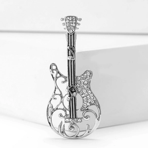 Macro detail of guitar brooch with silver alloy and sparkling white crystals on white stand