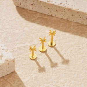 Detailed view of three gold star labret piercings on a textured beige stone surface