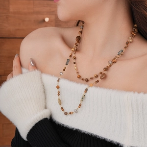 Detail of layered bohemian necklace with natural stones and golden metal chains