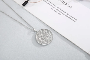 Close-up of silver hollow teardrop pendant necklace with crystals on a textured surface