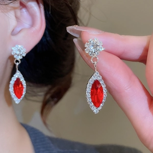 Macro detail of silver drop earring with a red marquise gem and crystal cluster