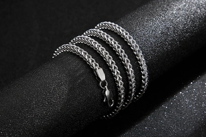 Macro shot of silver stainless steel wheat chain with lobster clasp on black background