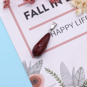 Faceted dark red teardrop stone pendant with silver clasp on a lifestyle background
