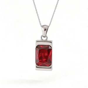 Detailed macro view of a silver rectangular pendant featuring a large emerald-cut red gemstone