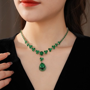 Dettaglio collana vintage con goccia di smeraldo e zirconi su abito in velluto