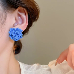 Close-up of bright blue resin flower stud earrings on model for a trendy summer look