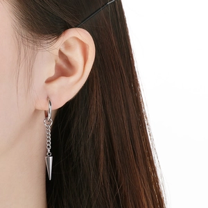 Close-up of a silver stainless steel hoop earring with a dangling chain and sharp cone pendant