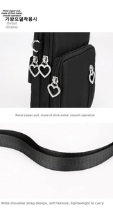 Detail of black crossbody phone bag with heart zipper pull and nylon strap