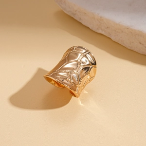 Close-up of wide textured metal cuff with irregular geometric patterns in 18K gold finish