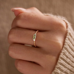 Detail of S925 silver ring with rectangular green zircon and gold plating on finger