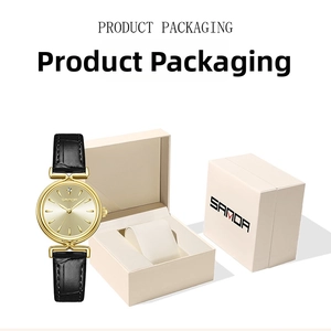 Close-up of SAMDA gold watch with black leather strap next to minimalist white gift box