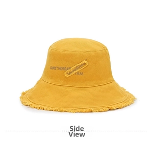 Detail of yellow cotton bucket hat with frayed edges and street style embroidery
