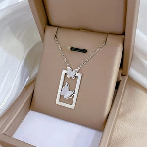 Close-up of silver butterfly frame pendant necklace inside a beige jewelry box