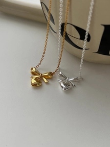 Detail of elegant gold and silver bow heart necklaces on a ceramic background