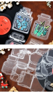 Detailed view of vintage PET butterfly stickers and glass bottle shapes on leather backdrop