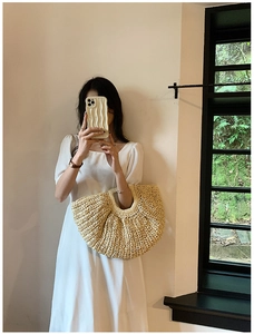 Handmade beige straw tote bag with half-moon shape and woven texture for summer beach