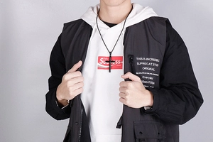 Collier avec pendentif croix noire simple en acier titane sur un mannequin homme, fond gris