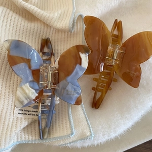 Elegant butterfly acetate hair claws in marble blue and amber brown for hair styling