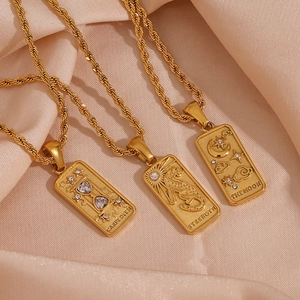 Macro shot of 18K gold plated tarot card pendants with twist chain on silk fabric