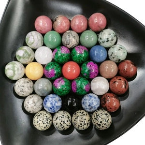 High-angle macro view of diverse natural crystal balls on a black triangular tray