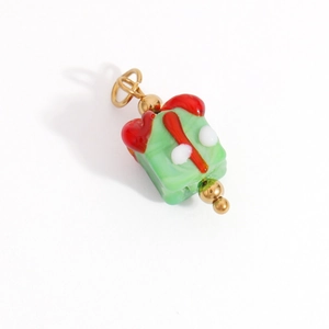 Macro detail of a green gift box pendant with red bow and gold metal beads for DIY jewelry