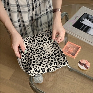Fashionable leopard print canvas cosmetic bag held by hand in a stylish setting