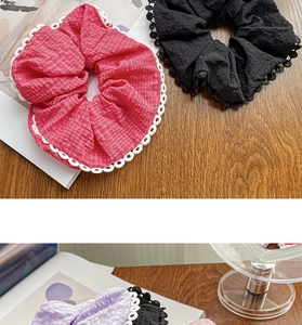 Detailed shot of red and black textured scrunchies with white lace edges on wood