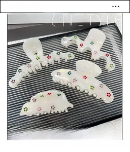 Detailed view of pearlescent acetate hair claws set with colorful rhinestone floral accents