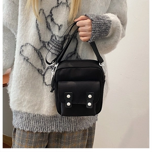Detail of black canvas crossbody bag with white buckles and adjustable strap texture