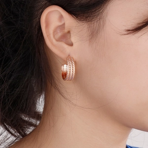 Detail of rose gold C-shaped earrings with wheat pattern on model's ear