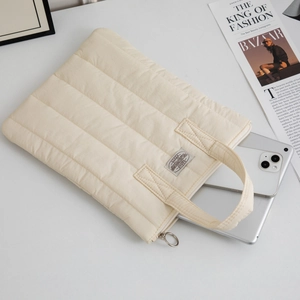Detail of cream quilted 13-inch laptop bag with soft padding and silver ring zipper