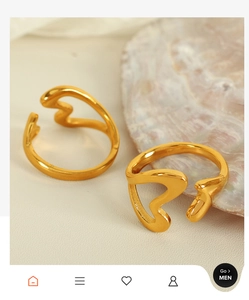 Close-up of elegant gold hollow heart rings on a pearl shell and textured surface