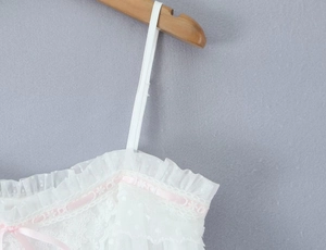 Nahaufnahme des weißen Spitzen-Unterhemds mit rosa Schleife und feinen Stickerei-Details