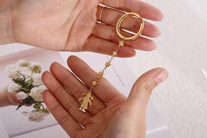 Detailed view of a golden stainless steel keychain featuring heart and figure pendants