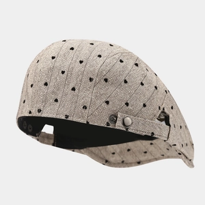 Beige herringbone newsboy cap with black heart pattern and side metal buckle
