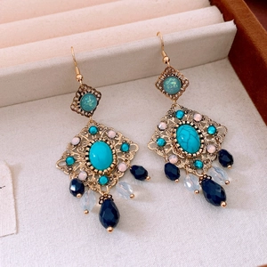 Détail de boucles d'oreilles vintage avec turquoise et glands dans un écrin de luxe