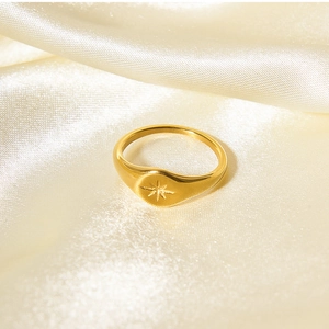 Detail shot of a polished gold signet ring with starburst engraving on champagne silk