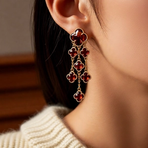 Macro detail of cascading red clover drop earrings with elegant 18k gold plating