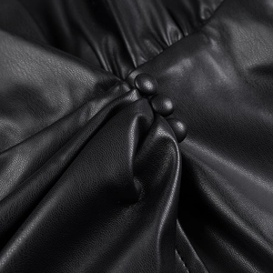 Détail d'une robe en cuir PU noir avec plis faits main et boutons recouverts assortis