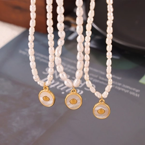 Elegant freshwater pearl necklace with gold shell pendant on a magazine background
